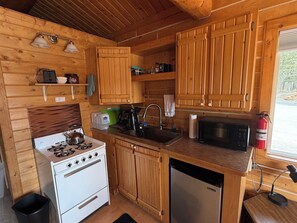 Une cuisine de taille réduite, dotée de meubles en bois, d’une cuisinière, d’un évier, d’un four à micro-ondes et d’un lave-vaisselle.