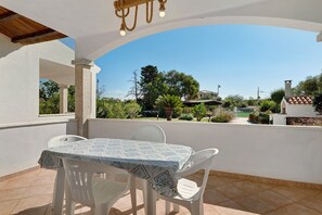 An outdoor patio with a table and chairs, a clear view of the surrounding landscape, and a building with a tiled roof in the background. - Apartment 'Annina' with Private Terrace, Wi-Fi and Air Conditioning (Pittulongu)