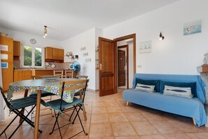 A compact living space with a dining area, kitchenette, and a sofa. - Apartment 'Annina' with Private Terrace, Wi-Fi and Air Conditioning (Pittulongu)