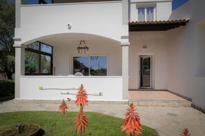 A modern two-story house with a covered patio, large windows, and a well-maintained lawn. - Apartment 'Annina' with Private Terrace, Wi-Fi and Air Conditioning (Pittulongu)