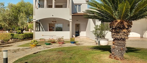 Una casa de dos pisos con techo plano, balcón y césped bien cuidado.
