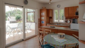 A kitchen with a dining area, a sliding glass door leading to an outdoor patio, and a view of the surrounding area. - Apartment 'Annina' with Private Terrace, Wi-Fi and Air Conditioning (Pittulongu)