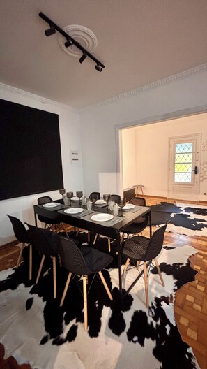 A dining area with a table set for six, black chairs, a cowhide rug, and a projector screen on the wall.