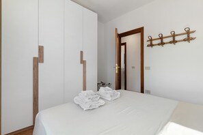 Un dormitori amb un llit, un armari, una porta i un assecador de tovalloles fixat a la paret.