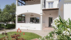 A two-story house with a balcony, a small garden, and a door. - Apartment 'Zio Tonino' with Private Terrace, Wi-Fi and Air Conditioning (Pittulongu)
