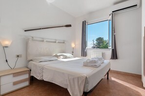 A bedroom with a bed, bedside lamps, a window with curtains, and a radiator. - Apartment 'Zio Tonino' with Private Terrace, Wi-Fi and Air Conditioning (Pittulongu)
