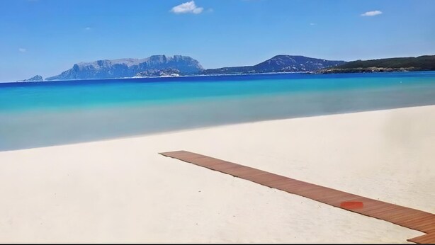A beach with clear water, a wooden deck, and distant mountains. - Apartment 'Zio Tonino' with Private Terrace, Wi-Fi and Air Conditioning (Pittulongu)