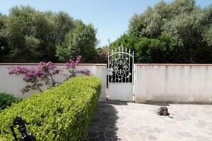 A gated entrance with a metal gate, a stone pathway, and a neatly trimmed hedge. - Apartment 'Zio Tonino' with Private Terrace, Wi-Fi and Air Conditioning (Pittulongu)