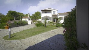 A residential area with a paved pathway leading to a white house with a tiled roof. - Apartment 'Zio Tonino' with Private Terrace, Wi-Fi and Air Conditioning (Pittulongu)