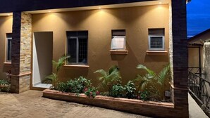 A building with a flat roof, multiple windows, and a paved entrance area with plants.