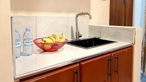 A kitchen with wooden cabinets, a black sink, and a bowl of bananas on the countertop.