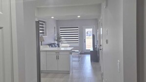 A hallway leading to a kitchen with a window, a door, and a ceiling light. - Stylish Secondary Suite with Private Entry (Airdrie)
