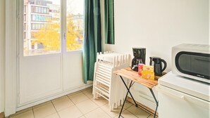 Una cuina petita equipada amb microones, cafetera i una taula amb una caixa de mocadors.
