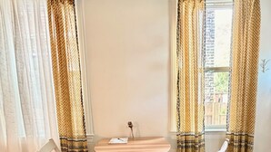 A room with a round wooden table, two white chairs, and patterned curtains. - Light-Filled Boho Studio Alcove Retreat in Philly’s Best Neighborhood , new Deck (Philadelphia)
