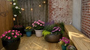 A wooden deck with potted plants and a brick wall. - Light-Filled Boho Studio Alcove Retreat in Philly’s Best Neighborhood , new Deck (Philadelphia)