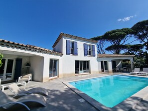 Ein zweistöckiges Haus mit Swimmingpool, Sitzgelegenheit im Freien und einer Pergola.