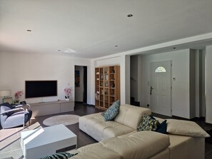 Ein modernes Wohnzimmer mit einer Couch, einem Flachbildfernseher, einem Bücherregal und einer Tür.