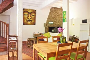 Ein Essbereich mit Holztisch und -stühlen, einem Steinkamin und einem Buddha-Gemälde an der Wand.