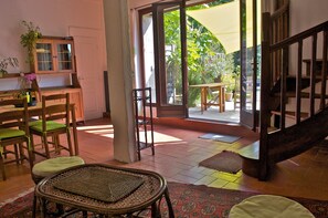 Ein Zimmer mit Esstisch, Stühlen, einem Schrank und Blick ins Freie.