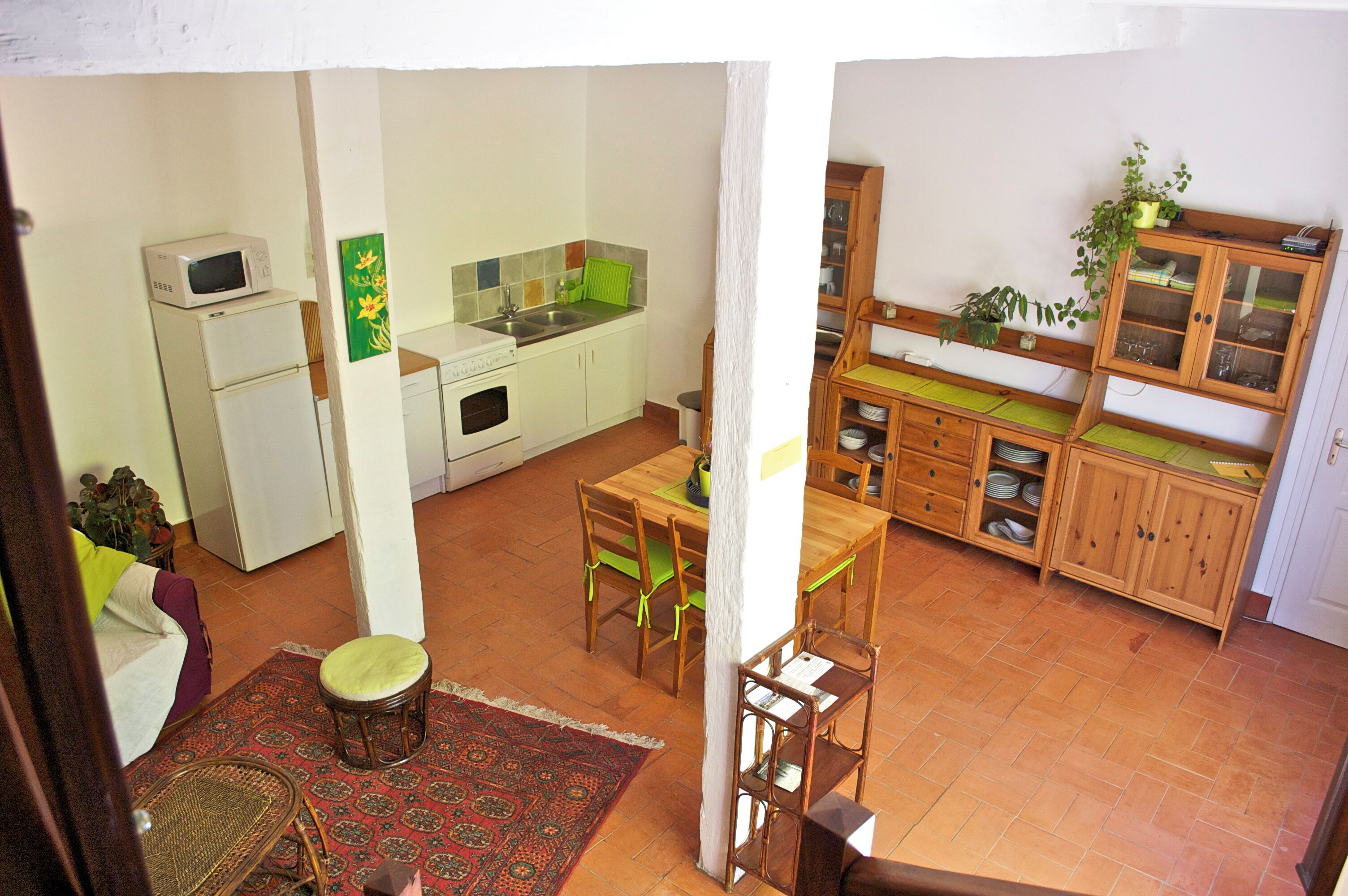 A compact kitchen with a dining area, a refrigerator, a microwave, and a cabinet with glass doors.