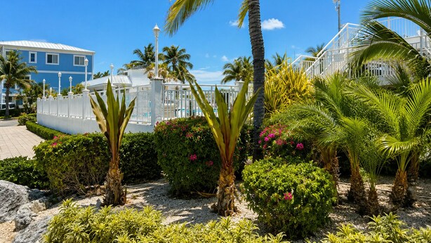 Un resort con cerca blanca, palmeras y un edificio azul.