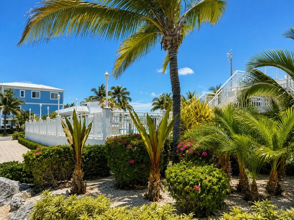 Ein Resort mit weißem Zaun, Palmen und einem blauen Gebäude.