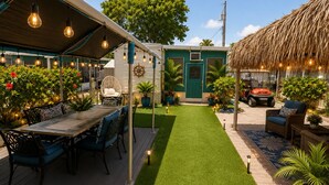 Un patio con una mesa de comedor, sillas y una estructura de techo de paja.