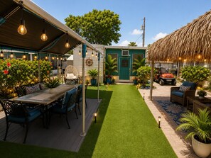 Ein Patio mit Esstisch, Stühlen und einer Reetdachkonstruktion.