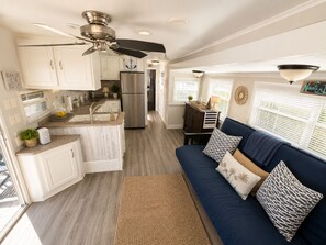 Eine kompakte Küche mit einer zentralen Kochinsel, ein Essbereich mit einem blauen Sofa und einem Deckenventilator.