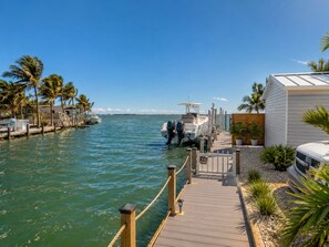 A marina with boats docked, a wooden walkway, and a building with a white exterior. - Tropical Key Largo Retreat | 2BR Coastal Cottage (Key Largo)