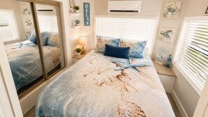Un dormitorio con un espejo grande, una cama con diseño de estrella de mar, un aire acondicionado de pared y un cartel que dice 'RELAX'.