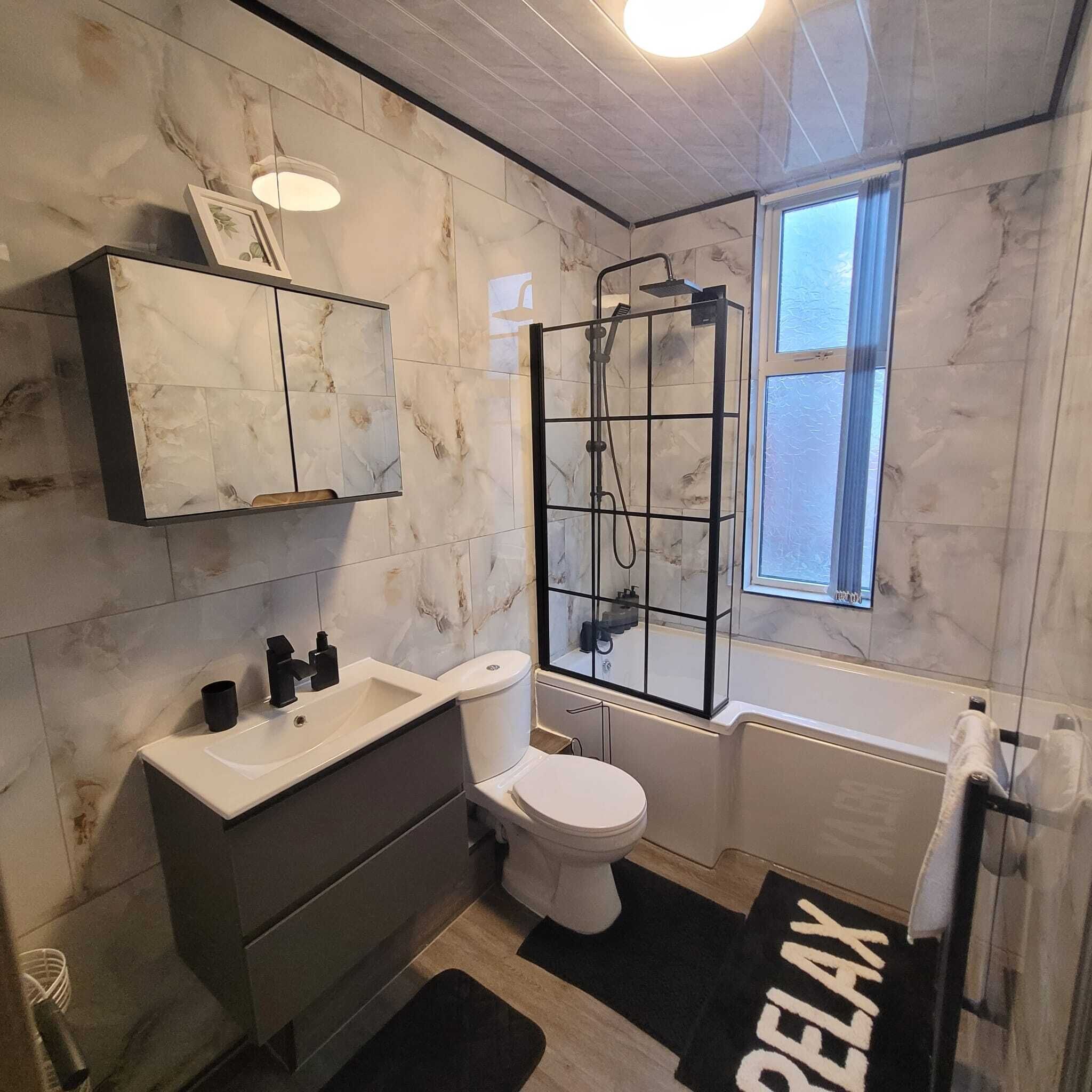 Un baño con ducha, inodoro, lavamanos y ventana.