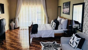 Een kamer met een bed, een slaapbank, een bureau en een plafondventilator.