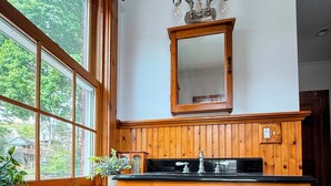 A wooden kitchen with a large window, a sink, and a mirror above it.