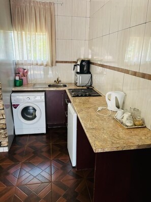 A compact kitchen with a washing machine, a coffee maker, and a kettle. - Studio in Golden Acres – Kwekwe - 2371 (Kwekwe)