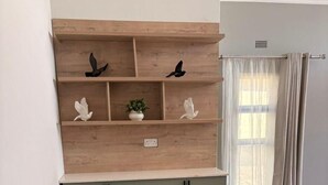 Een keuken met een houten wandrek, een werkblad en keukenkastjes.