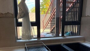 Een keuken met een raam, een spoelbak en een metalen afdrukkers.
