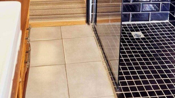Una habitación con piso de baldosas, un comedor con mesa y sillas, y una cocina con estufa y alacenas.