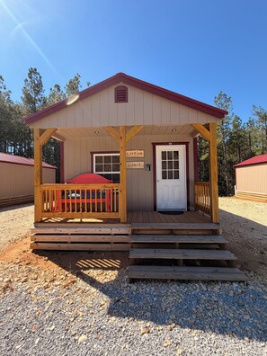 A small cabin with a porch, a red bench, and a door labeled 'CATFISH CABIN'. - BRAND NEW!!  1-bedroom cabin with 2  Queen beds. Near PICKWICK LAKE (Iuka)