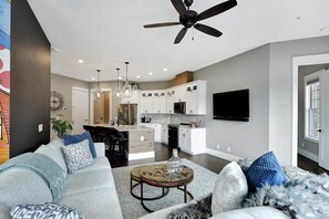 A modern living room with a sofa, coffee table, and a kitchen in the background.