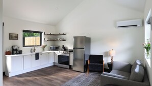 A compact kitchen with a built-in oven, a refrigerator, and a microwave. There is a dining area with a table and chairs. - Steps from the Lake- Sauna + Hot Tub. Entire 7 Unit Inn (Jones)