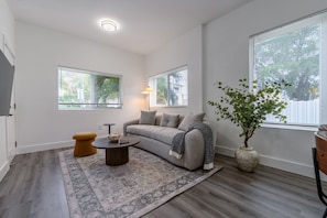 A modern living room with a sofa, coffee table, and a potted plant. - 2BR Steps from Downtown  In-Unit Washer and Dryer (Miami)
