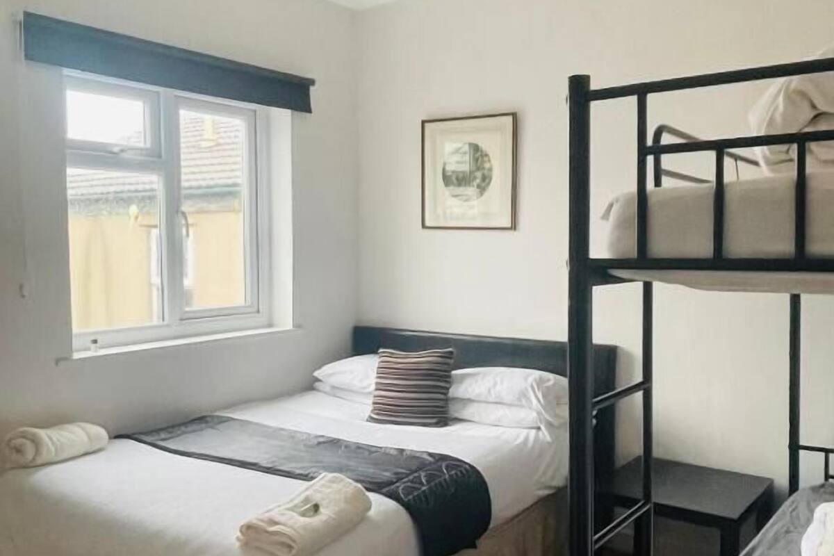 A bunk bed room with a window, a framed picture on the wall, and a hanging light fixture.