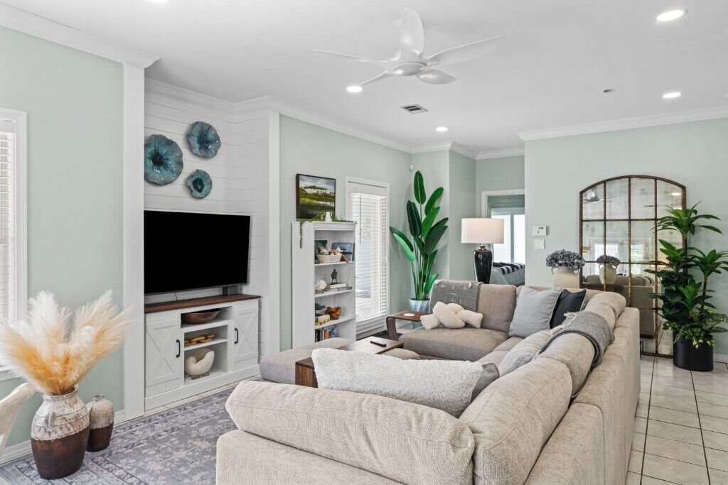 Un salon comprenant un canapé, un téléviseur, un ventilateur de plafond et des objets décoratifs.