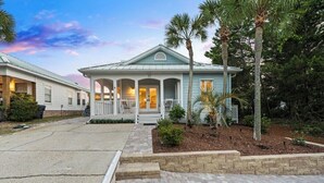 A single-story house with a porch, a small garden with palm trees, and a paved driveway. - Private 30A Beach Retreat - Coastal Backyard Oasis (Santa Rosa Beach)