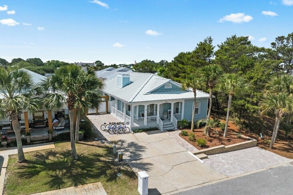 A coastal house with a porch, bicycles, and palm trees.