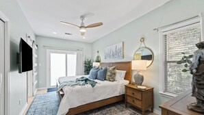 A bedroom with a bed, nightstand, lamp, ceiling fan, artwork, and a window with blinds. - Private 30A Beach Retreat - Coastal Backyard Oasis (Santa Rosa Beach)