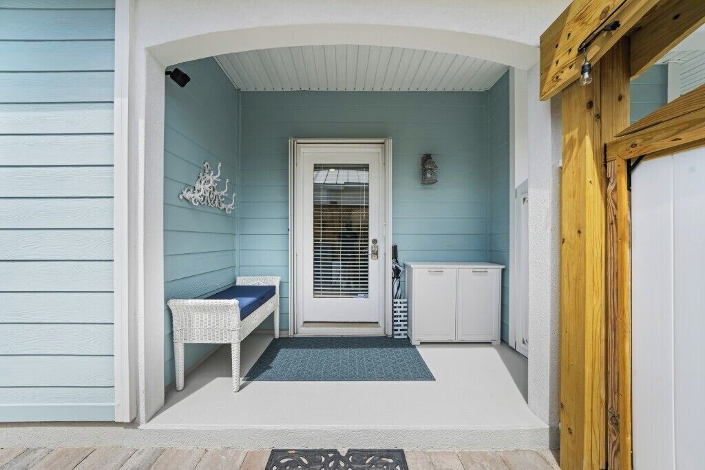 A porch with a bench, a door, a small cabinet, and a light fixture.