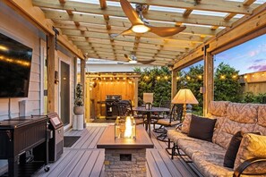 Eine überdachte Terrasse im Freien mit Feuerstelle, Sitzgelegenheiten und Grillbereich.