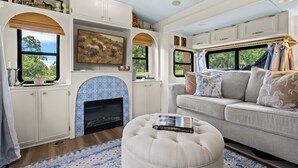 Un interno camper accogliente con un caminetto, un divano e un libro intitolato 'The Horse Encyclopedia'.